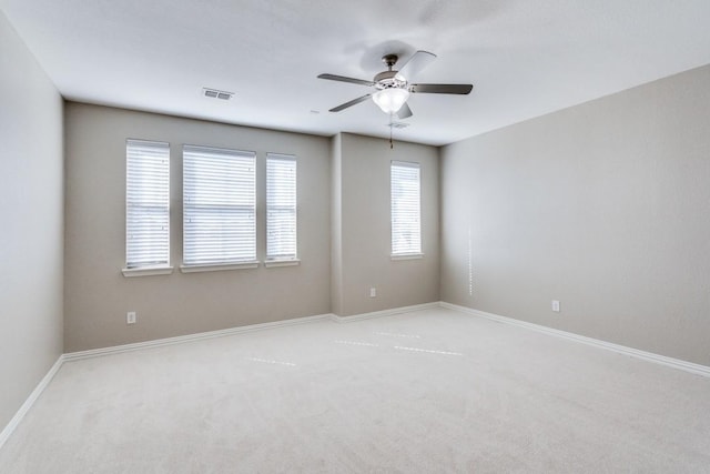 empty room with light carpet, ceiling fan, visible vents, and baseboards