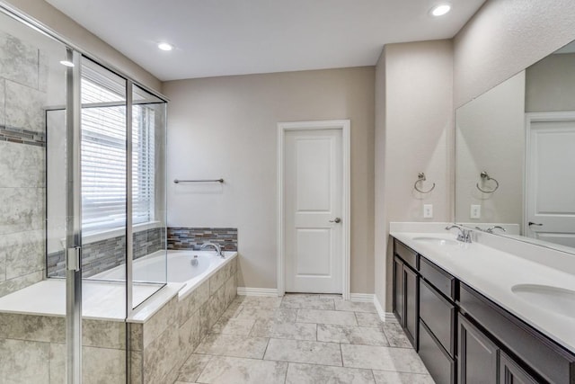 full bath with double vanity, a sink, a bath, and baseboards