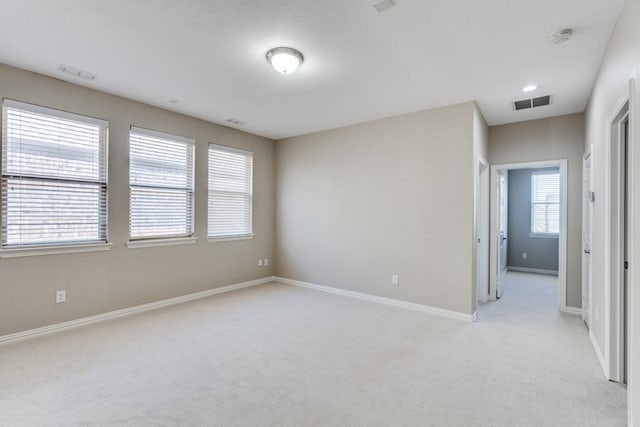 empty room with visible vents, light carpet, and baseboards