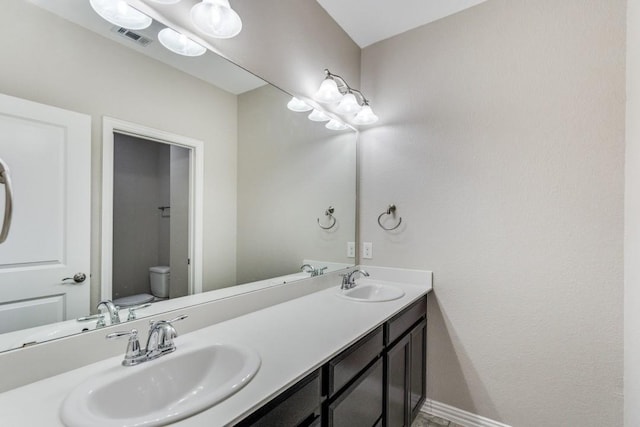 full bathroom with visible vents, a sink, toilet, and double vanity