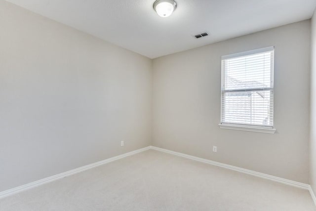 unfurnished room featuring light colored carpet, visible vents, and baseboards