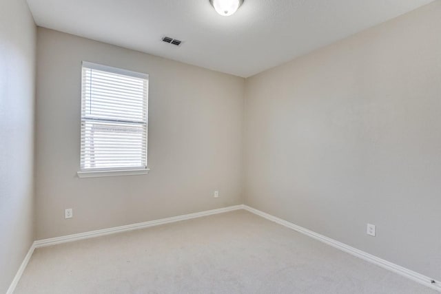 spare room featuring carpet, visible vents, and baseboards