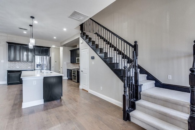 kitchen with stainless steel appliances, wood finished floors, visible vents, baseboards, and light countertops