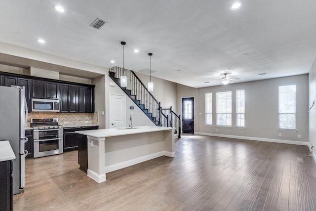 kitchen with stainless steel appliances, light countertops, light wood-type flooring, and visible vents