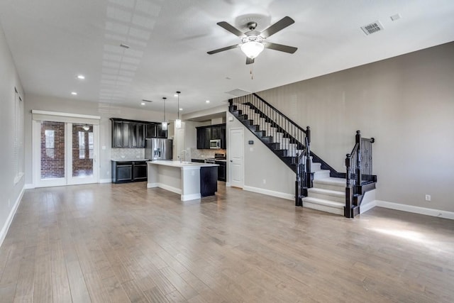 unfurnished living room with visible vents, a sink, wood finished floors, baseboards, and stairs