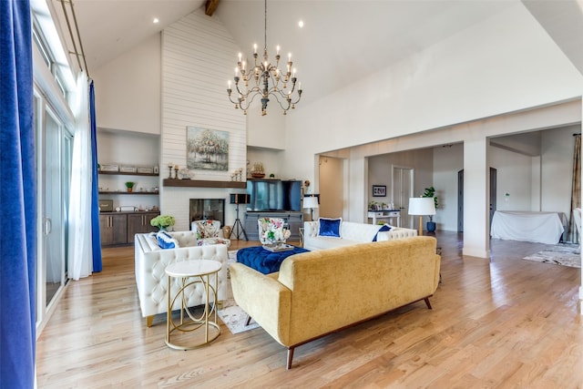 living area with beam ceiling, high vaulted ceiling, a brick fireplace, a chandelier, and light wood-type flooring