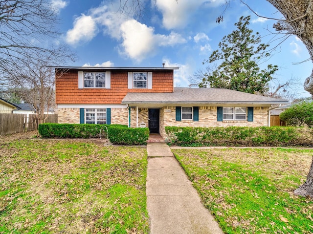 view of front of house featuring a front yard, fence, and brick siding