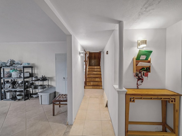 corridor featuring stairway, a textured ceiling, and tile patterned floors