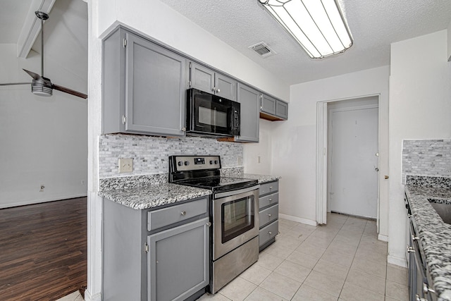 kitchen featuring visible vents, gray cabinets, electric stove, black microwave, and tasteful backsplash