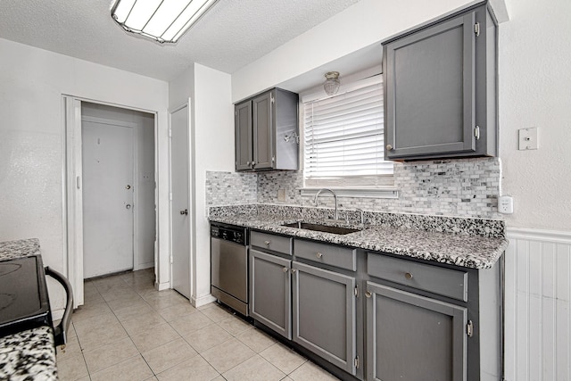 kitchen with dishwasher, gray cabinetry, light tile patterned floors, and a sink