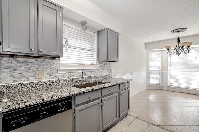 kitchen featuring light tile patterned floors, a wainscoted wall, a sink, gray cabinetry, and dishwasher