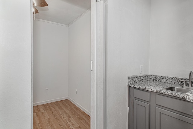 interior space with a sink, light wood-type flooring, baseboards, and a ceiling fan