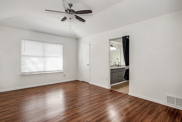 interior space with dark wood-style floors, baseboards, visible vents, vaulted ceiling, and a textured ceiling