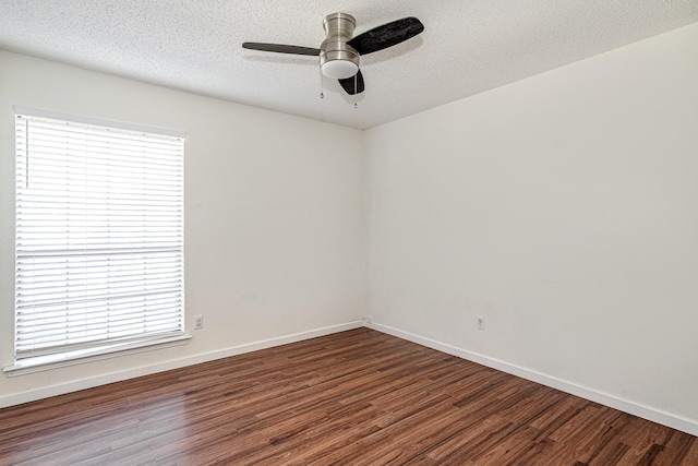 empty room featuring a textured ceiling, baseboards, and wood finished floors