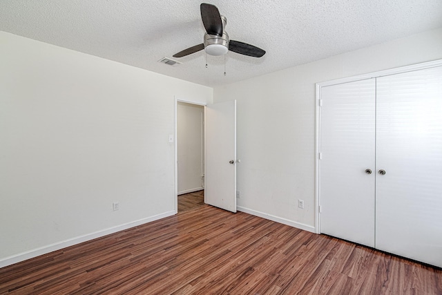 unfurnished bedroom with visible vents, a textured ceiling, wood finished floors, a closet, and baseboards