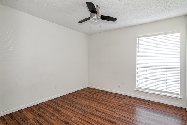 empty room featuring a wealth of natural light, a textured ceiling, and dark wood-style flooring