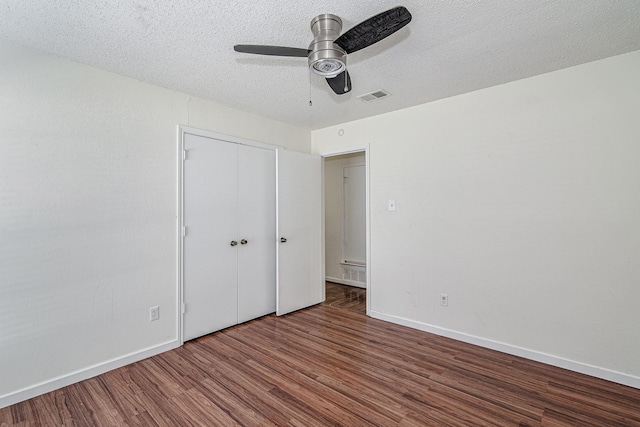 unfurnished bedroom featuring visible vents, a textured ceiling, wood finished floors, a closet, and baseboards