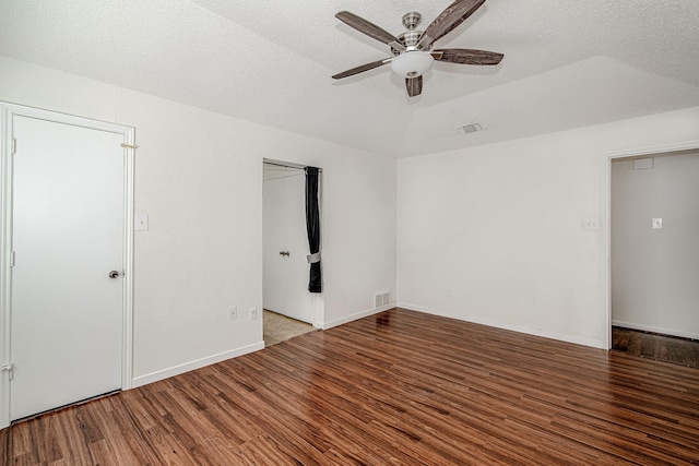 unfurnished room featuring visible vents, a textured ceiling, wood finished floors, and vaulted ceiling