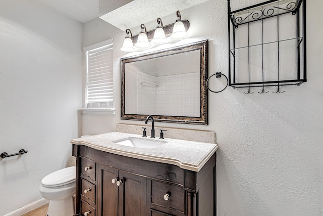 bathroom featuring baseboards, toilet, vanity, and a textured wall