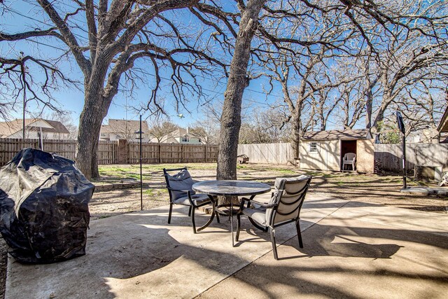 view of patio with an outbuilding, a fenced backyard, outdoor dining space, and a shed