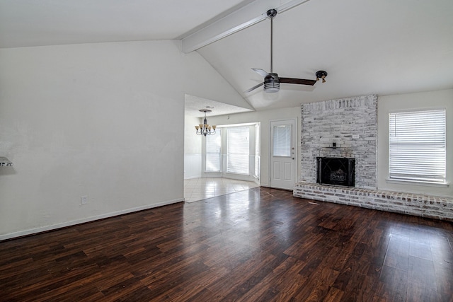 unfurnished living room with a brick fireplace, baseboards, beam ceiling, ceiling fan with notable chandelier, and wood finished floors