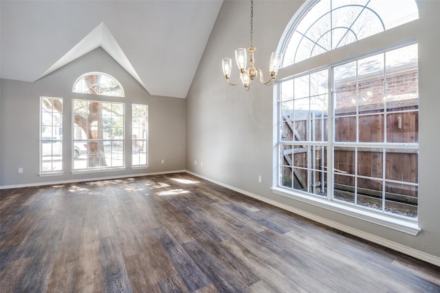 empty room with high vaulted ceiling, baseboards, a notable chandelier, and wood finished floors