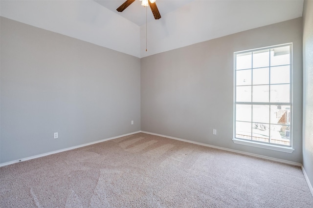 carpeted empty room featuring a ceiling fan, vaulted ceiling, and baseboards