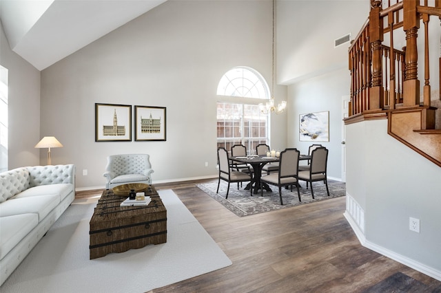 living area featuring baseboards, visible vents, dark wood-style flooring, an inviting chandelier, and high vaulted ceiling