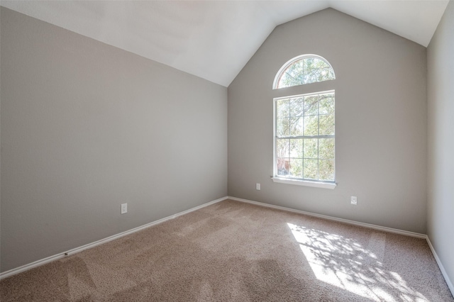 carpeted empty room featuring vaulted ceiling, plenty of natural light, and baseboards