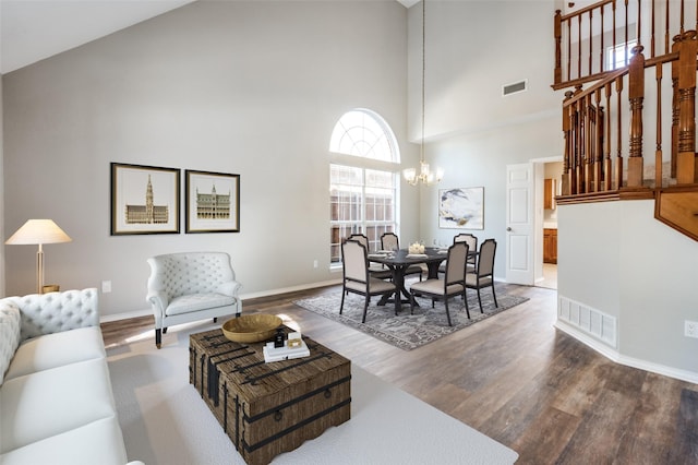 dining room with baseboards, visible vents, wood finished floors, a high ceiling, and a notable chandelier