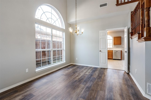 unfurnished dining area with a notable chandelier, visible vents, baseboards, and wood finished floors