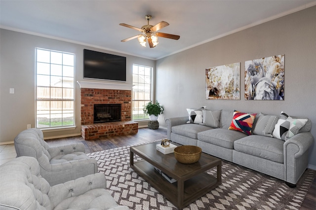 living room featuring baseboards, a ceiling fan, ornamental molding, wood finished floors, and a fireplace