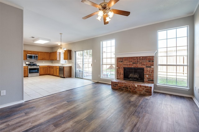 unfurnished living room with a healthy amount of sunlight, light wood-style floors, baseboards, and crown molding