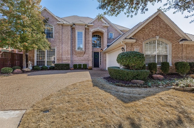 traditional-style home with a garage, fence, concrete driveway, and brick siding