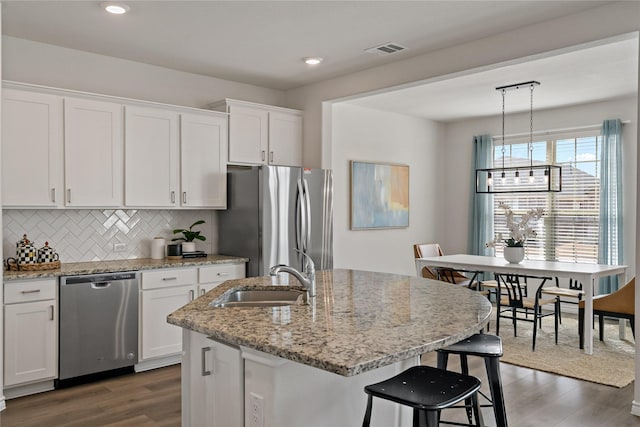 kitchen with appliances with stainless steel finishes, dark wood finished floors, white cabinetry, and a sink