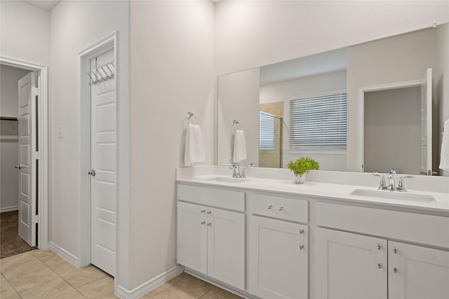 bathroom with tile patterned flooring, a walk in closet, a sink, and double vanity