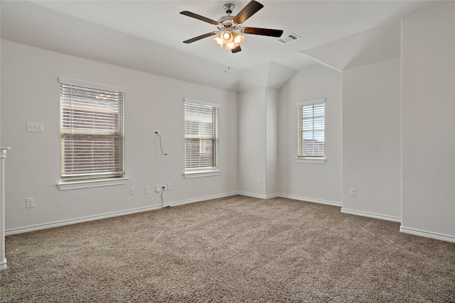 carpeted empty room featuring baseboards, lofted ceiling, visible vents, and a ceiling fan