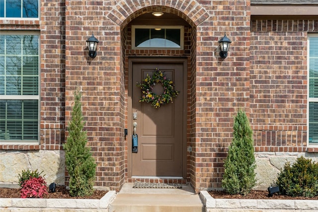 view of exterior entry featuring brick siding