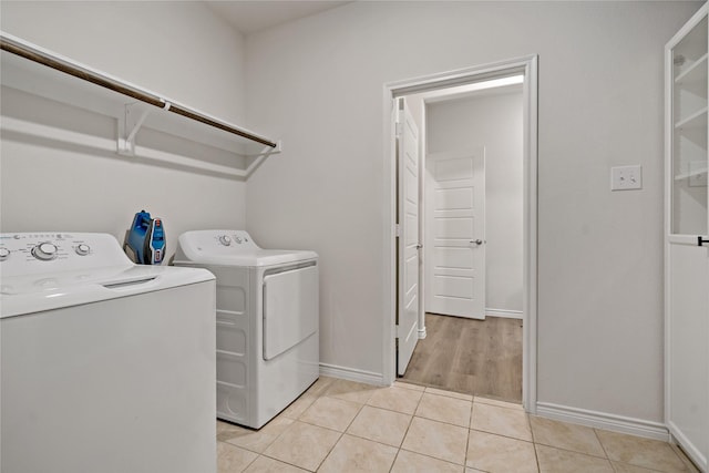 clothes washing area featuring laundry area, light tile patterned floors, baseboards, and separate washer and dryer