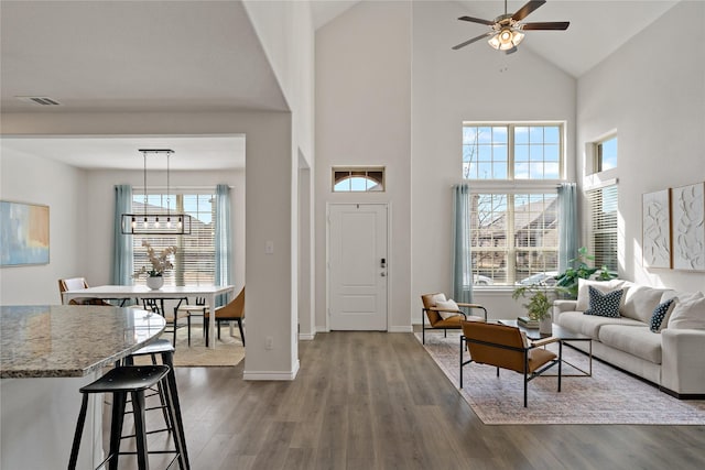 entrance foyer featuring dark wood-style floors, visible vents, high vaulted ceiling, baseboards, and ceiling fan with notable chandelier