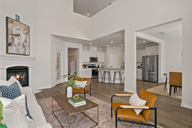 living area with a glass covered fireplace, visible vents, and dark wood finished floors