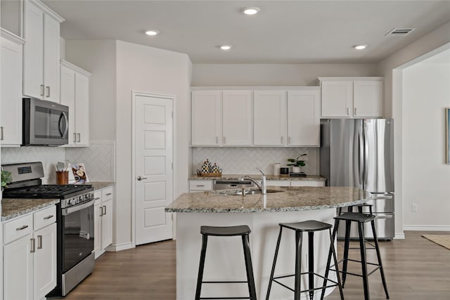 kitchen featuring stainless steel appliances, wood finished floors, a sink, and white cabinets