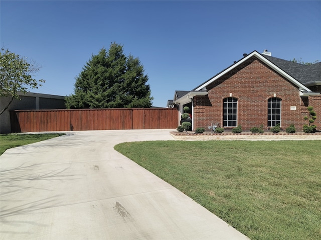 view of side of property with a yard, fence, and brick siding