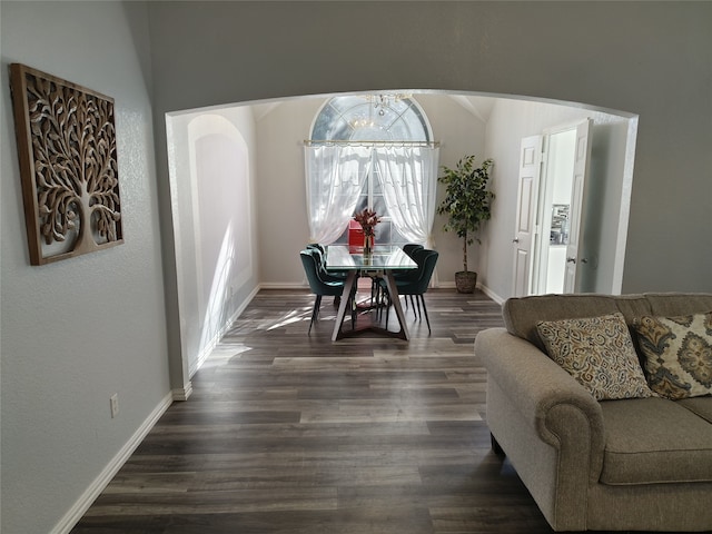 dining room with baseboards, arched walkways, vaulted ceiling, and dark wood-style flooring