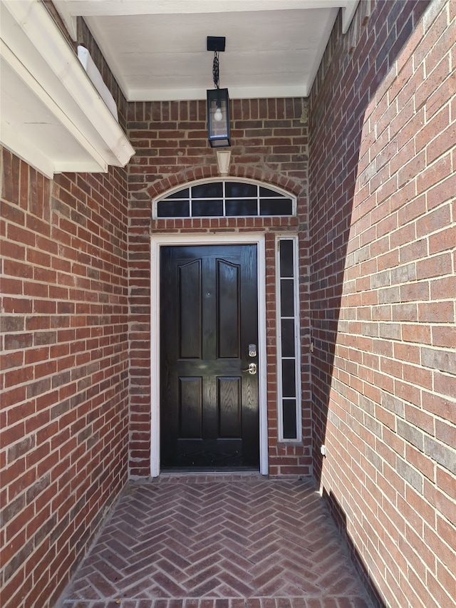 view of exterior entry featuring brick siding