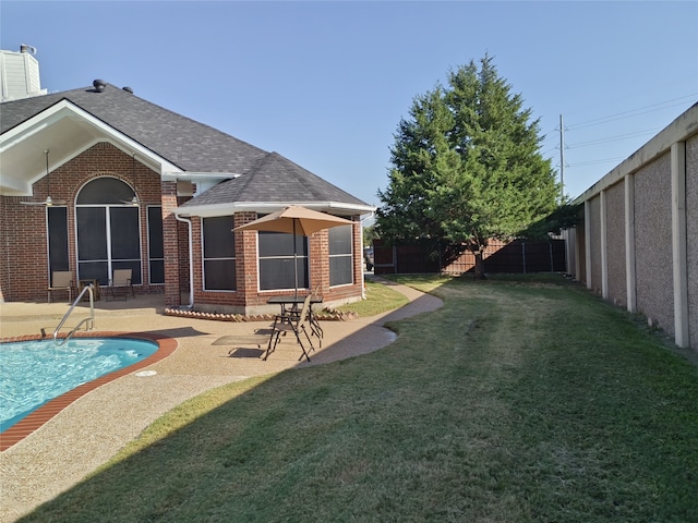 back of house with a lawn, a patio, a fenced backyard, roof with shingles, and brick siding