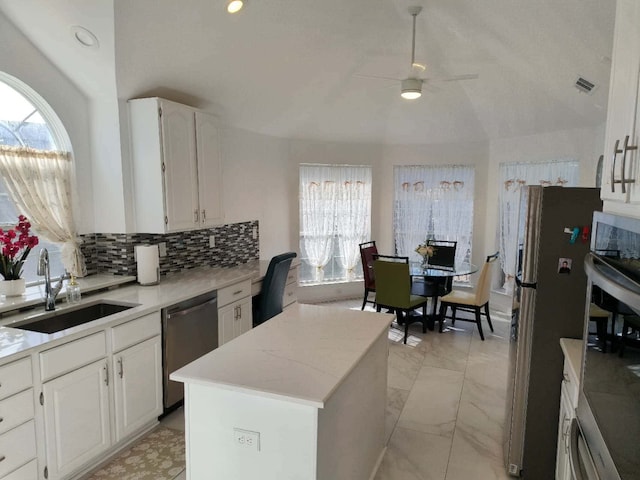 kitchen with lofted ceiling, visible vents, appliances with stainless steel finishes, white cabinetry, and a sink