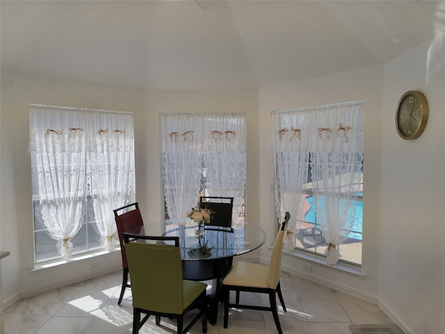 dining space with lofted ceiling, tile patterned floors, and baseboards