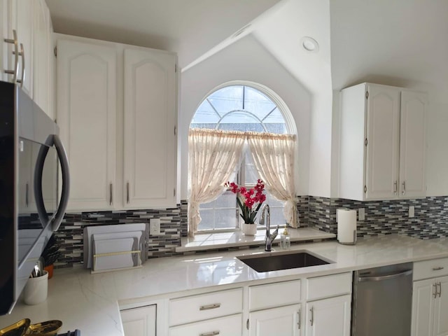 kitchen with backsplash, white cabinetry, stainless steel appliances, and a sink