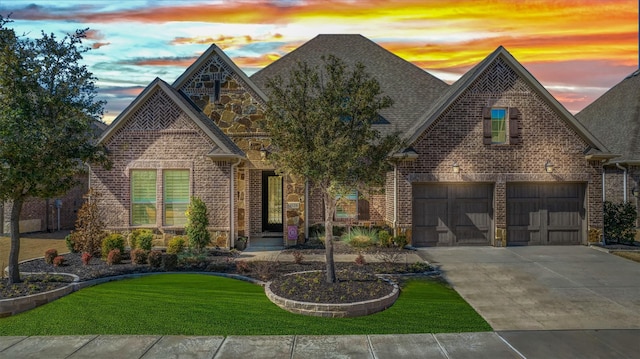 view of front of house with driveway, stone siding, an attached garage, and brick siding